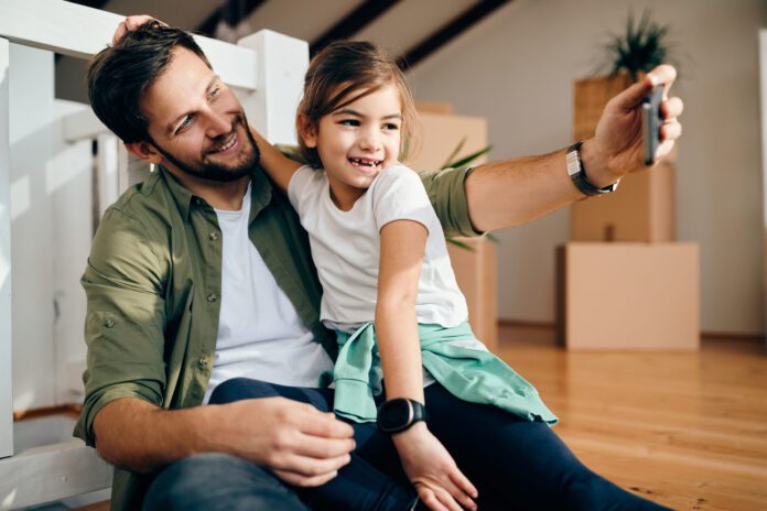 Happy single father and his daughter taking selfie after moving